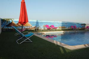 达喀尔Hotel Fleur De Lys Almadies的一个带椅子和遮阳伞的游泳池以及游泳池