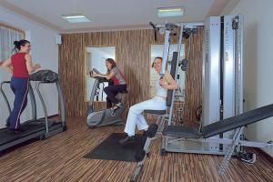 巴迪亚Hotel San Leonardo的一名男子和两名妇女在健身房锻炼