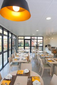 亚眠Logis hôtel - La Chambre D'Amiens的餐厅设有白色的桌椅和窗户。