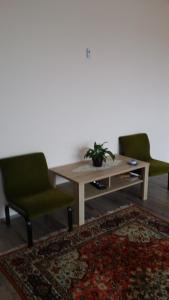 莫劳豪洛姆Maros Vendégház的客厅配有桌子和两把绿色椅子