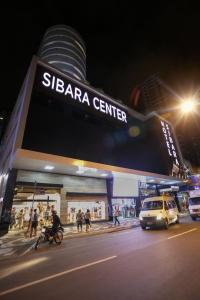 巴拉奈里奥-坎布里乌Hotel Sibara SPA & Convenções的夜间的巴拉中心,门前有车辆停放