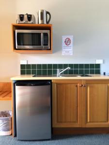 凯恩斯大炮公园汽车旅馆的厨房配有不锈钢冰箱和微波炉。