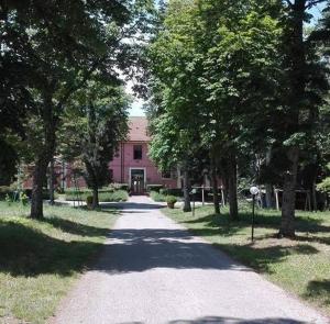 廖内罗因武尔图雷Country House Villa delle Rose Agriturismo的一条通往一座有树木的粉红色建筑的道路
