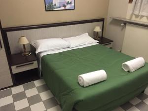米兰亚诺酒店的一间卧室配有绿床和毛巾