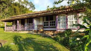 康塞高伊比蒂波卡Pousada Meu Recanto的粉红色的房子,设有门廊和院子