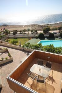 厄尔梅达诺Apartment El Medano Sunrises的阳台配有桌子和两把椅子,游泳池