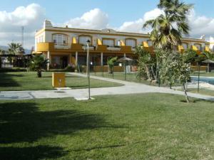 塔里法Livingtarifa La Tortuguita的一座黄色的建筑,有棕榈树和游泳池