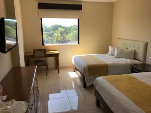 卡门城Hotel Del Viajero的酒店客房设有两张床和窗户。