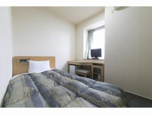 丰桥市冈田丰桥商务酒店的一间卧室配有一张床、一张书桌和一个窗户。