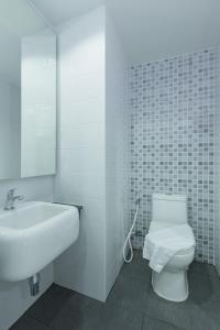 Samut Sakhon通臣公寓酒店的白色的浴室设有卫生间和水槽。