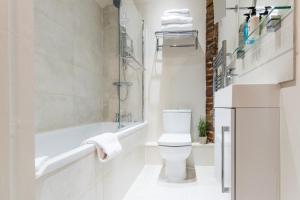 威布里治April House Weybridge - Boutique Guesthouse的白色的浴室设有卫生间和浴缸。