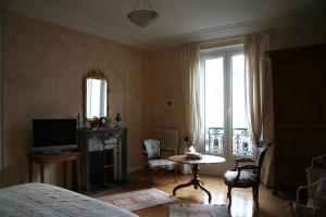 勒芒Chambres d'hôtes Le Clos d'Hauteville的一间卧室配有一张床、一台电视和一张桌子