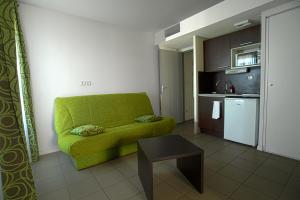 蒙法维KOSY Appart'Hôtels - Campus Del Sol Esplanade的一间带绿色沙发的客厅和一间厨房