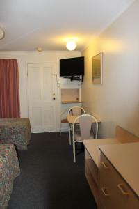 麦克斯维尔中部海岸汽车旅馆的酒店客房带一张床、一张桌子和椅子