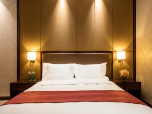 顺义北京临空假日酒店的一间卧室配有一张带两盏灯的大型白色床。