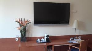 瓦伦西亚Hotel RH Sorolla Centro的墙上的电视,桌子上放着花瓶