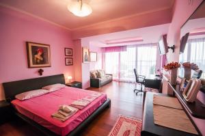 新安希亚洛斯Holidays Pelion的粉红色的卧室设有床和客厅。
