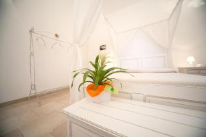 佩斯科勒海滨Antica Masseria Ficazzana - Tenuta的卧室配有白色的床和桌子上的植物