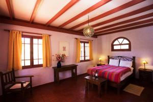 Hurtado洛斯安第斯庄园酒店的一间卧室设有床和两张桌子及窗户。
