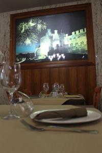 蓬费拉达埃尔卡斯特洛酒店的餐厅里一张桌子、酒杯和电视