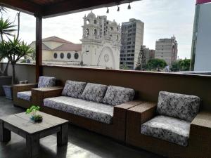 利马Lima Wasi Hotel Miraflores的阳台设有沙发和两把椅子,阳台与大楼相连