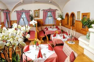 Laimbach am Ostrong施赖纳 - 达斯瓦德菲特尔酒店的餐厅设有桌子和红色椅子,并种植了鲜花。