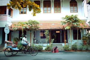 蓬蒂切里Maison Perumal Pondicherry - CGH Earth的一个人在一座建筑物前骑着自行车,带着狗
