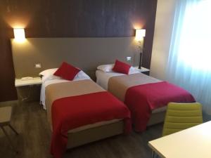 菲利内瓦尔达诺托斯卡纳酒店的酒店客房带两张红色和白色的床单