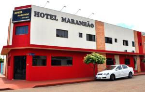 欧里尼奥斯Hotel Maranhão的前方有白色汽车的红色和白色建筑