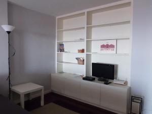 马托西纽什Apartamento Fonte Luz II的一间客厅,在白色的墙上配有电视