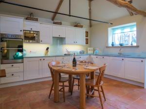 FressingfieldAppletree Cottage Fressingfield的厨房配有白色橱柜和一张带椅子的木桌