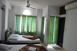 库克斯巴扎Hotel Shams Plaza的一间卧室设有两张床和绿色窗帘