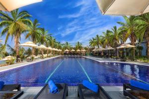 富国Amarin Resort & Spa Phu Quoc的一座棕榈树和遮阳伞的游泳池