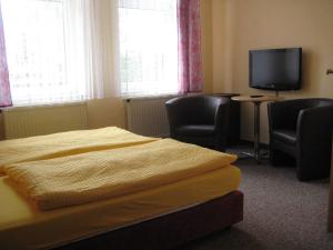 卑尔根格塞施法兹酒店的一间卧室配有一张床、两把椅子和一台电视