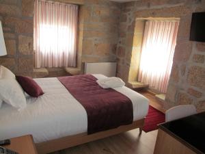 圣佩德罗温泉Hotel Solar da Capela的一间卧室设有一张大床和两个窗户。