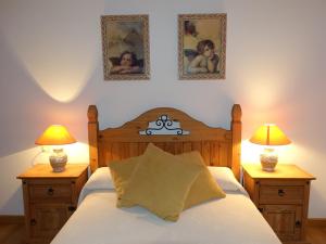 Vitigudino拉托尔托拉度假屋的一间卧室配有一张带两盏灯的床,墙上有两张照片