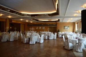 巴特嫩多夫斯齐德伽斯特豪斯吉尔克罗曼蒂克酒店的宴会厅配有白色的桌椅