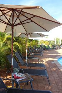 埃克斯茅斯埃克斯茅斯世外度假酒店的一组椅子和遮阳伞,位于游泳池旁
