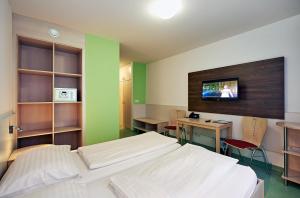 维也纳Hotel Kolping Wien Zentral的客房设有两张床、一张桌子和一台电视机。
