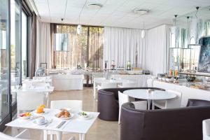 圣乔瓦尼-因马里尼亚诺海滨高尔夫度假酒店的餐厅设有白色的桌椅和窗户。