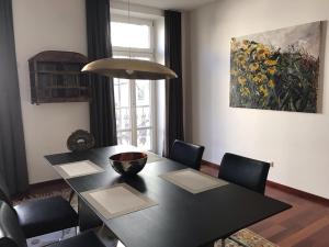 萨尔茨堡仙境公寓的一张黑色餐桌,配有椅子和绘画作品