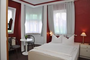 迈宁根安德尔卡佩勒酒店的卧室配有白色床、红色墙壁和窗户