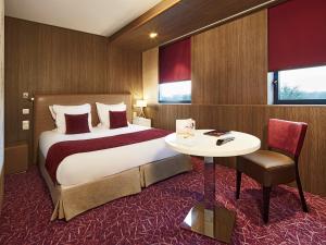 岩尼维利昂内维尔金色郁金香酒店的酒店客房设有一张大床和一张桌子。