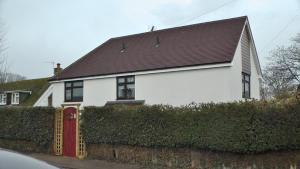伯青顿Bay Lodge的一间白色的房子,有红色的门和树 ⁇ 