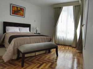 库斯科奎维公寓的一间卧室配有一张床、一张长凳和一个窗户。