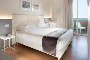 里米尼Hotel Ascot & Spa的卧室配有一张白色大床和一把椅子