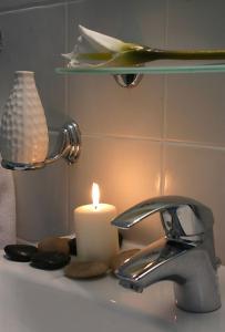 卢特拉艾季普苏海上客房&别墅公寓式酒店的蜡烛坐在水龙头旁边的水槽上