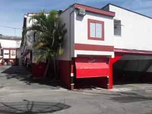 圣保罗Motel Sedução的一座红白色的建筑,旁边是棕榈树