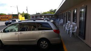 奥里利亚枫树汽车旅馆的停在一座带白色椅子的建筑旁边的银色货车