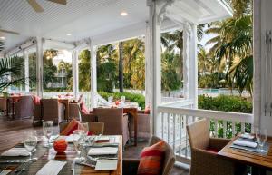 马拉松宁静湾度假酒店的一间设有桌椅的餐厅,种植了棕榈树